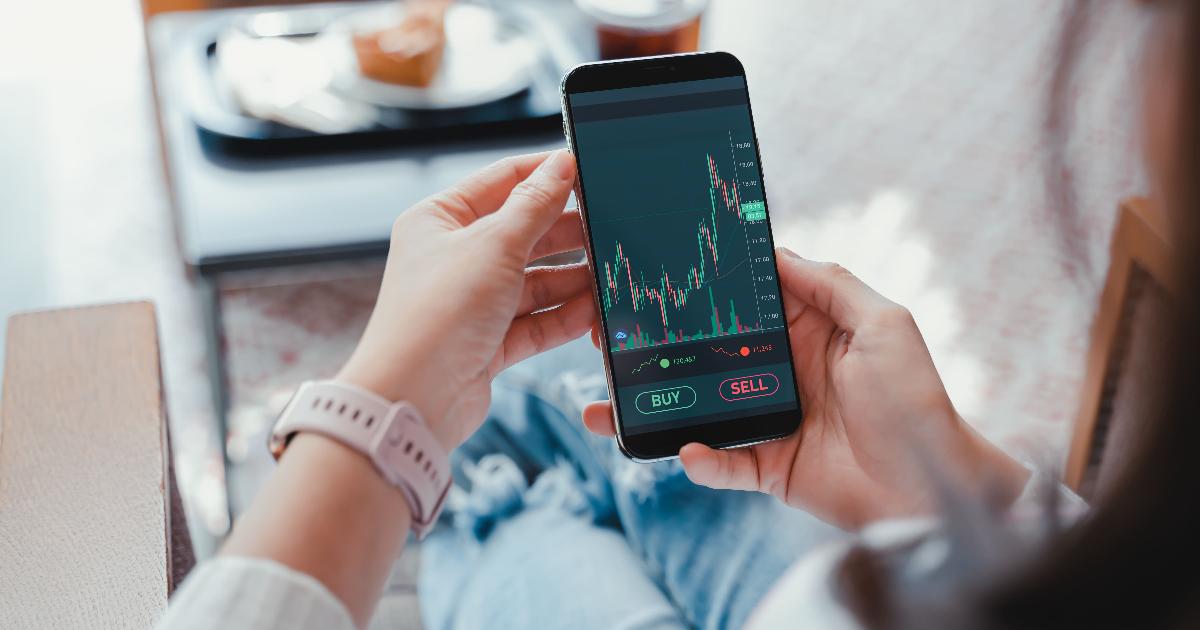 A person using a smartphone app to review an investing dashboard and automatic transfer settings